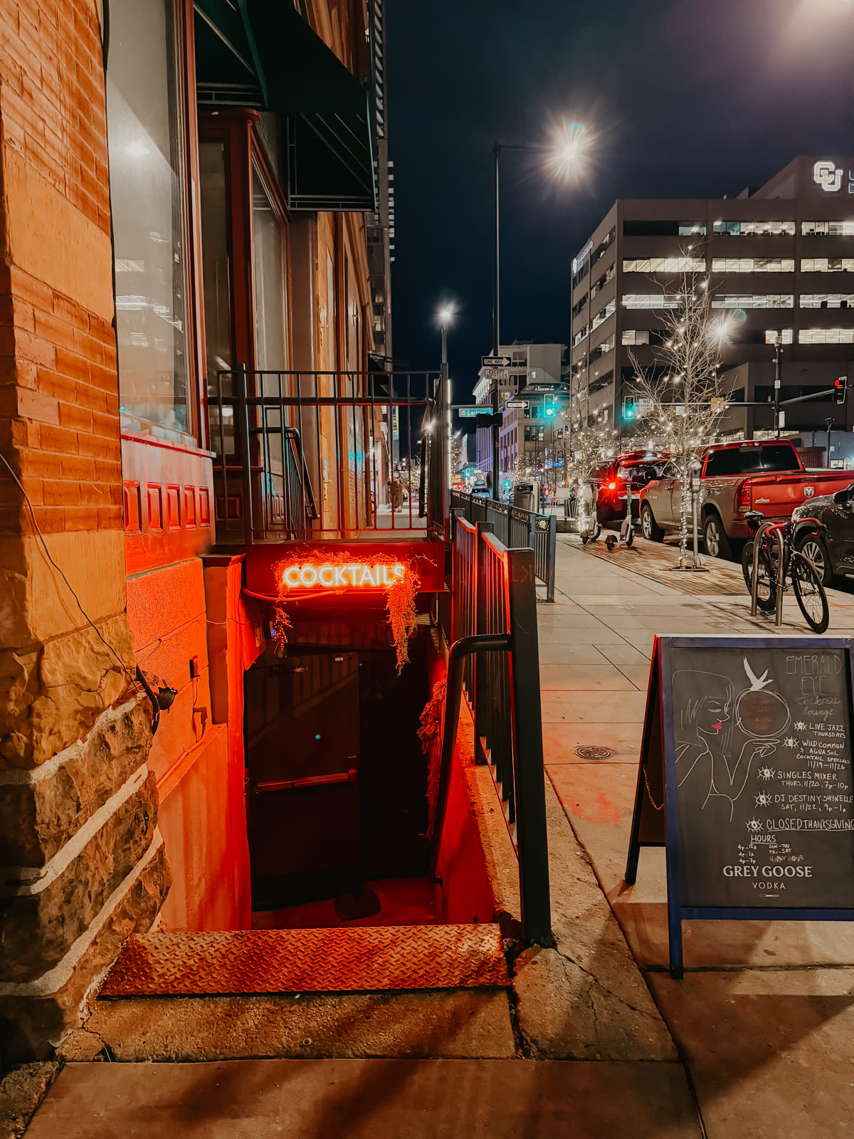 The Emerald Eye entrance on Larimer Street: a stairwell down from the sidewalk under a red COCKTAILS neon sign