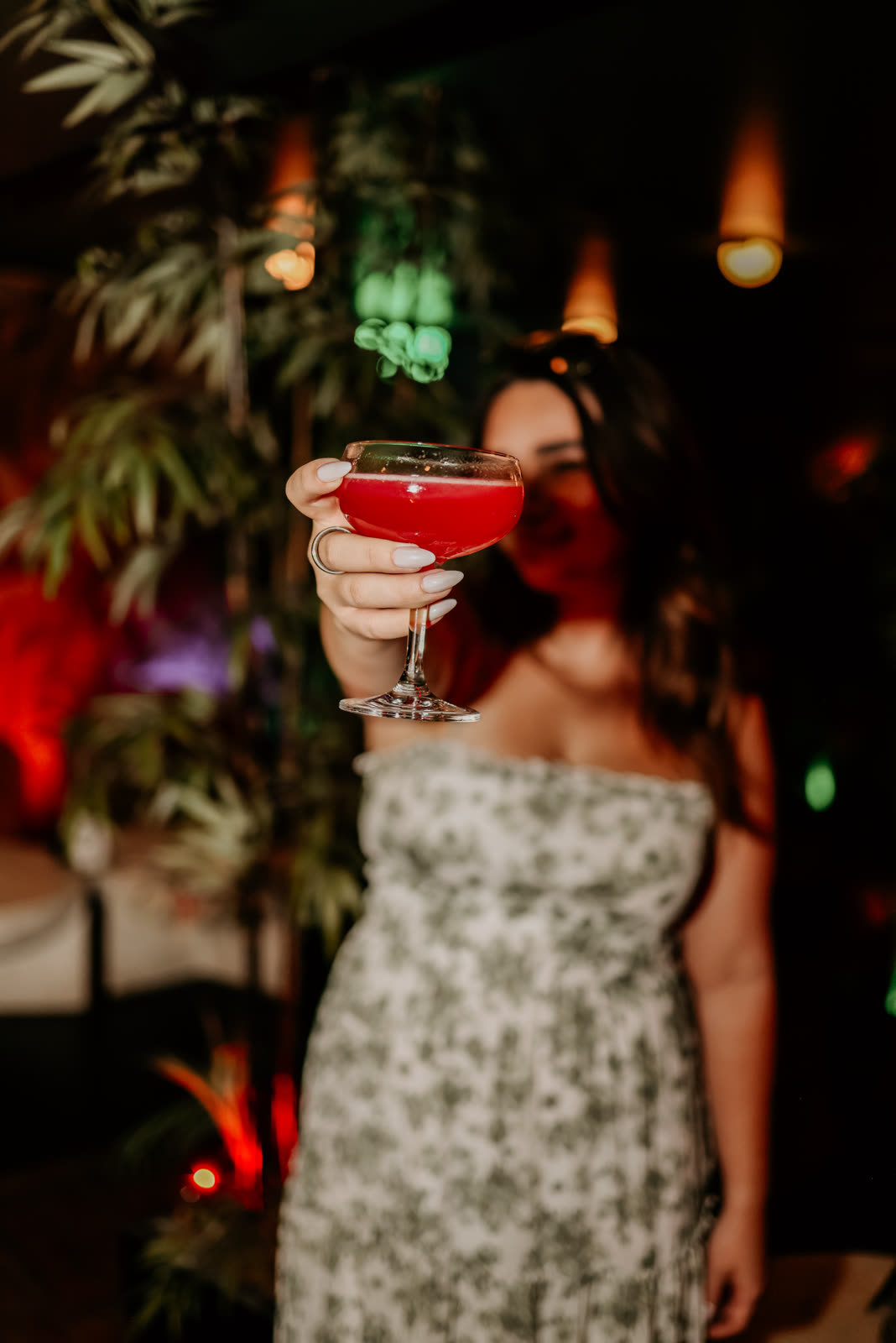 A guest raising a red coupe under green and red lights late in the night